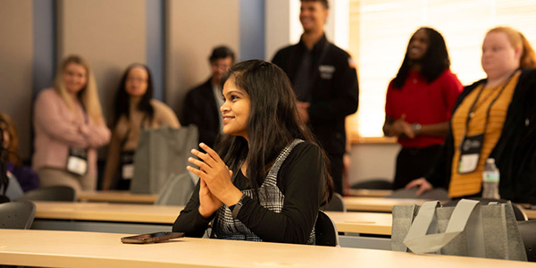 A student smiles and claps during a presentation.